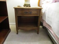 Front view of a single Thomasville night table showing drawer, open lower shelf, and feet with scalloped skirt detail.