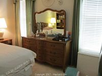 Dresser and mirror in bedroom setting shown with items on top, dresser drawers closed.