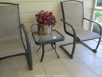 Square frosted glass patio table with two matching mesh patio chairs and floral arrangement on table