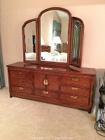 Front view of closed dresser with tri-fold mirror attached, showing brass hardware and burl wood finish.