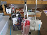 Side view showing toaster, fire extinguisher, air mattress box, step ladder and red cups on a wooden shelf