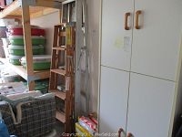 Photo showing two ladders side by side near shelving units and storage boxes, along with packages of Duraflame fire logs at the base.