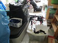View of overall lot showing black tub and dog wheelchair on white table, black garbage bag filled with items, laundry basket with bowls