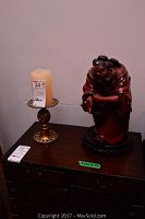 Overall view of brass candle holder and red clay figure on wood surface