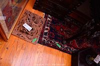 Photo of the wood carved square panel decor positioned next to the red geometric patterned carpet on hardwood flooring.