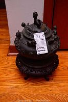 Front view of bronze incense burner with lid on carved wood stand