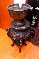 Full view of carved wood pedestal table supporting a metal bowl, showing overall lot composition