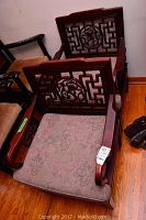 Two chairs angled side by side showing carved backs and cushions