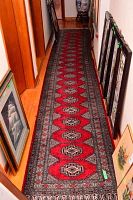 Full-length view of runner showing red field with repeating geometric medallions and black and ivory borders