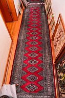 Full view of runner rug laid in hallway showing full length and repeating diamond medallion pattern