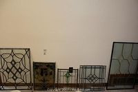 Five assorted stained glass window panels of varying sizes and designs arranged side by side on floor.