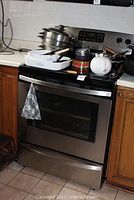 Kenmore stove in a kitchen setting surrounded by countertops and cabinets, with kitchenware placed on top.