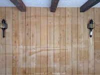 Pair of black metal wall sconces mounted on wooden wall with visible ceiling beams, showing overall size and style.