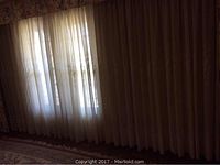 Sheer curtains hanging in front of a window with light filtering through, showing semi-transparent fabric.