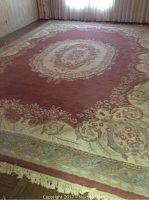Wool rug laid flat showing full rug and floral medallion pattern in red and cream tones.