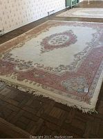 Full view of rug on parquet floor showing overall pattern and wear