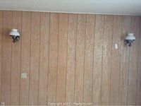 Pair of vintage hurricane style wall sconces mounted on wood panel wall