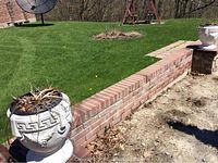 Both cement urns displayed outdoors near a brick wall, showing size and condition including wear and cracks.