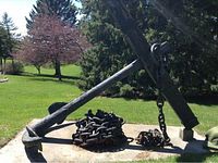Wide angle view of full anchor resting on concrete pad with coiled chain in front