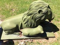 Side view of entire sculpture showing reclining adult lion and cub on rectangular base