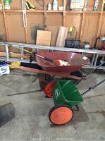 Wide view of garage corner showing ladder, wheelbarrow, seed spreader and weedwacker