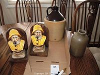Photo of 2 fisherman bust bookends, brown-topped crock, and B.C. Millburn jug on table