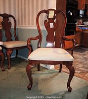 Front view of armchair showing carved mahogany frame and upholstered seat.