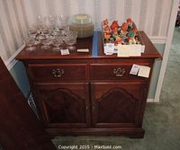Front view of wooden sideboard with drawers and cabinet doors, top surface holding items not included.