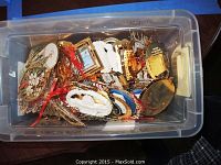 Plastic tote container filled with assorted metal and plastic ornaments of various shapes and sizes.