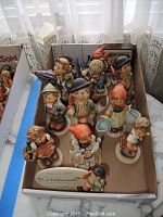 Overview of all figurines arranged in two rows inside a cardboard box