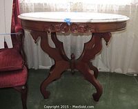 Front perspective view showing entire oval marble top and carved wood base