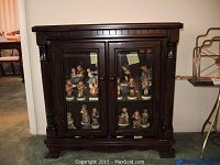 Front view of the cabinet with closed glass doors showing wood trim and knob handles