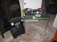 Overview of tools on table and wheeled tool chest next to cabinet in room