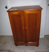 Front view of the cabinet showing two paneled doors with wooden knobs and block feet base.