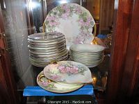 Full set of Welmar China plates and bowls with pink floral design and gold trim arranged in display cabinet.