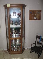 Front view of the wooden display cabinet with glass doors showing collectibles inside and cabinet wood finish.