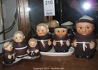 Full set of 6 monk ceramic figurines with dark brown robes and white belts arranged, including a ceramic tray.