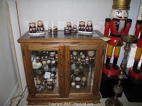 Front view of oak wood and glass display cabinet containing ceramic figurines.