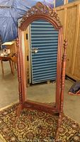 Front view of antique standing mirror showing full height and carved wooden frame details.