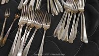 Forks and other flatware pieces showing stainless steel and silver-plated materials with some tarnishing and wear.