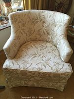 Front view of beige upholstered armchair with floral damask pattern.