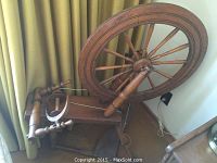 Full view of the vintage wooden spinning wheel showing the large drive wheel and supporting frame.