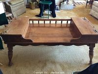 Full view of coffee table showing turned legs, hinged hinged side storage compartments, and front spindle detail.