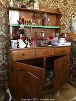 Full frontal view of wood hutch showing three drawers, two cabinet doors open slightly, open shelves above with various decorative items.