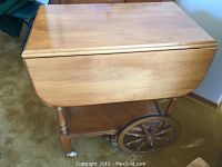 Maple tea cart showing closed drop-leaf top and wooden wheels.