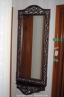 Wall-mounted rectangular mirror with dark brown ornate scrollwork composite frame.