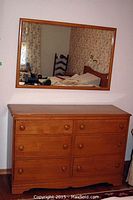 Maple finish dresser with six drawers from a slight angle, showing well-maintained wood surface and knob details.