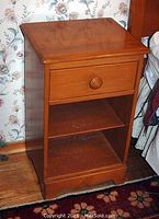 Photo showing the full night stand with drawer and two open shelves, maple finish wood, some wear visible.