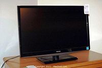 Full view of Toshiba flat panel television on stand showing black bezel and screen.