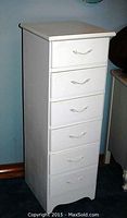 Full side and front view of tall skinny white painted dresser with six drawers and decorative handles.